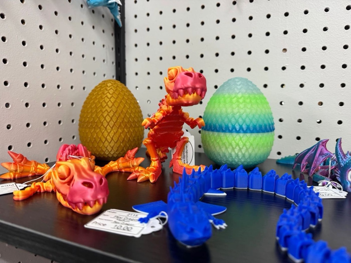 Gold and mint dragon eggs on a shelf with an orange T-rex and a long blue articulated dragon
