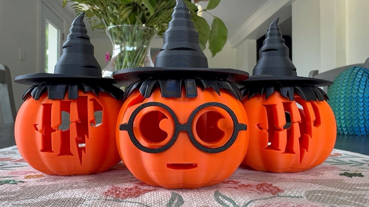 Three orange pumpkins wearing witch hats, one with round glasses