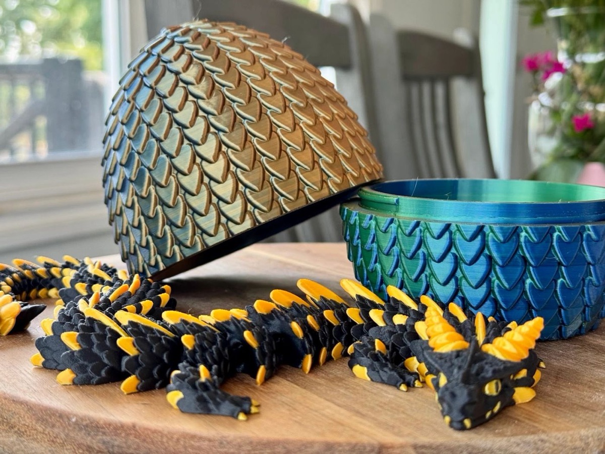 Gold-and-teal scaled dragon egg opened beside a black and gold articulated dragon