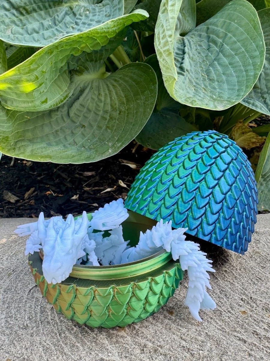 Green scaled dragon egg with a white crystal dragon climbing out