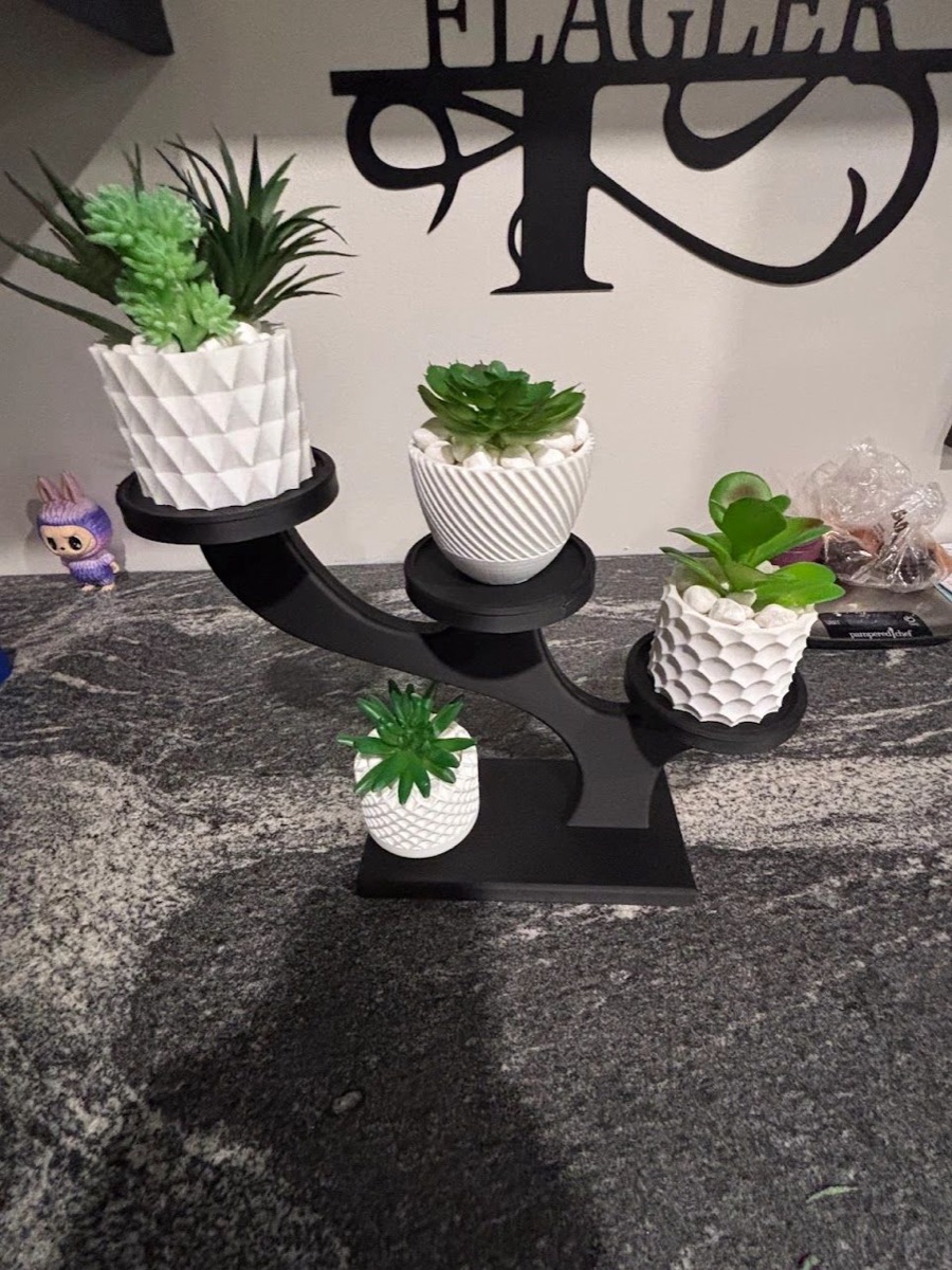 Black tree-shaped plant stand holding four white textured pots with succulents