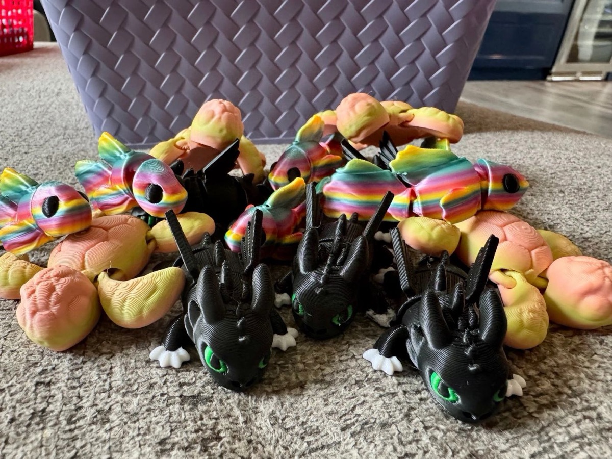 A pile of articulated dragons in rainbow, peach and black with green eyes